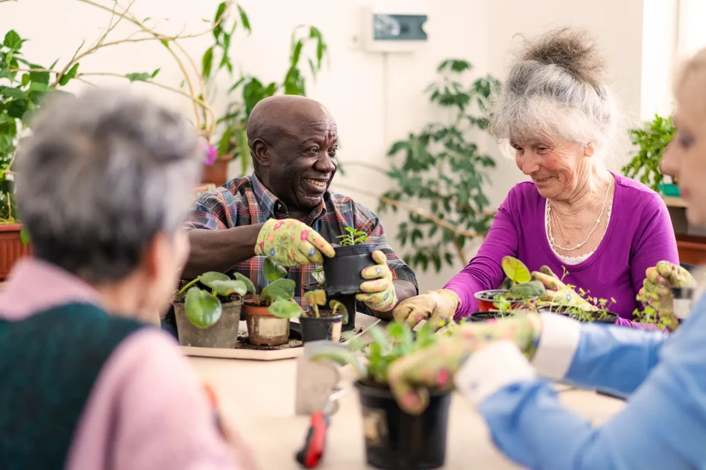 Seniors chatting together while potting up some plants and gardening for motor skill improvement