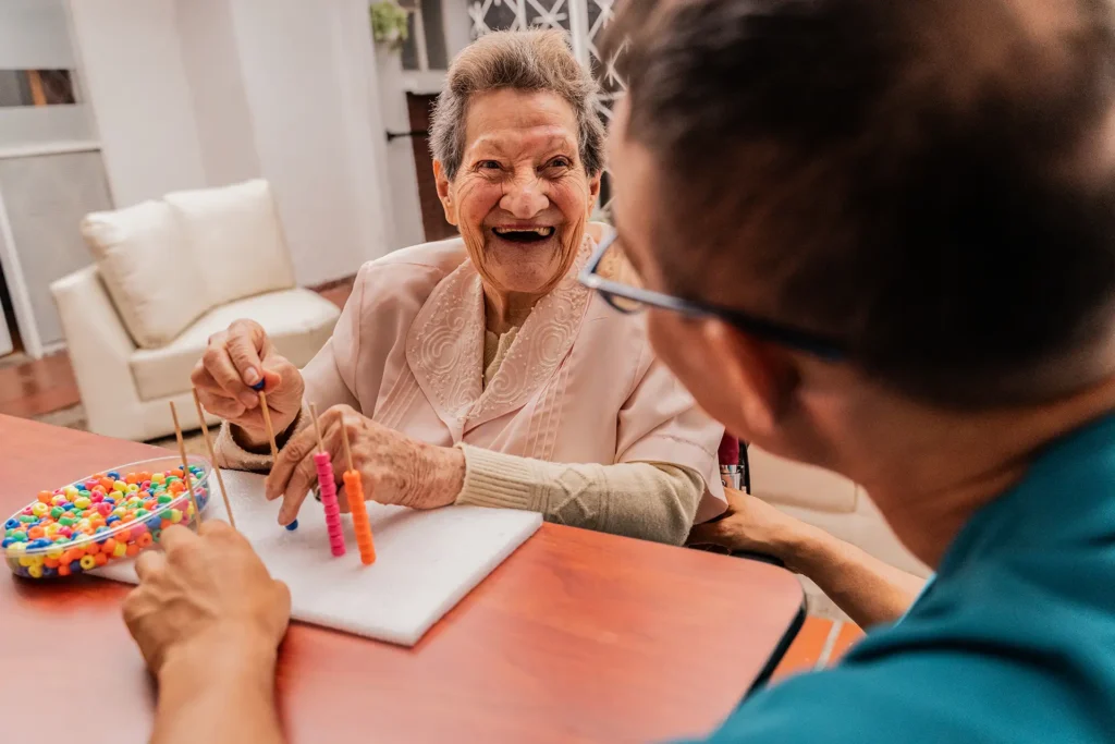 Senior woman and caregiver playing with abaco toy at home
