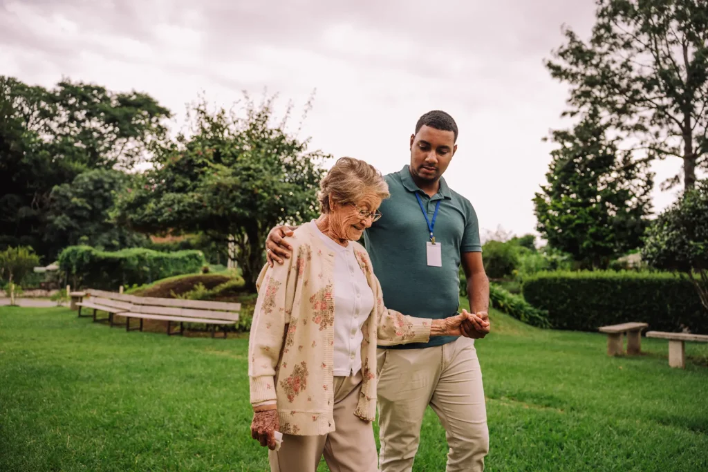 Senior woman walking with male caregiver outside